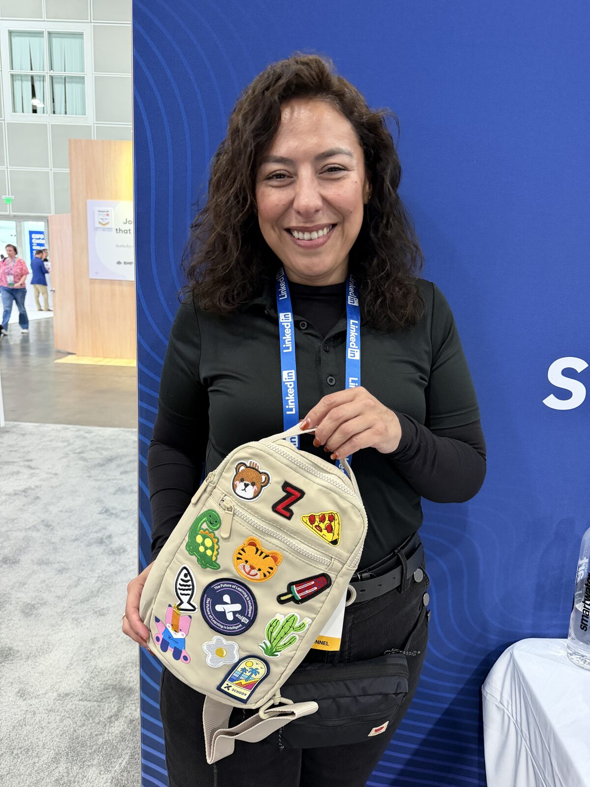 A guest holding a finished cream bag covered in embroidered letter and novelty patches at an expo booth