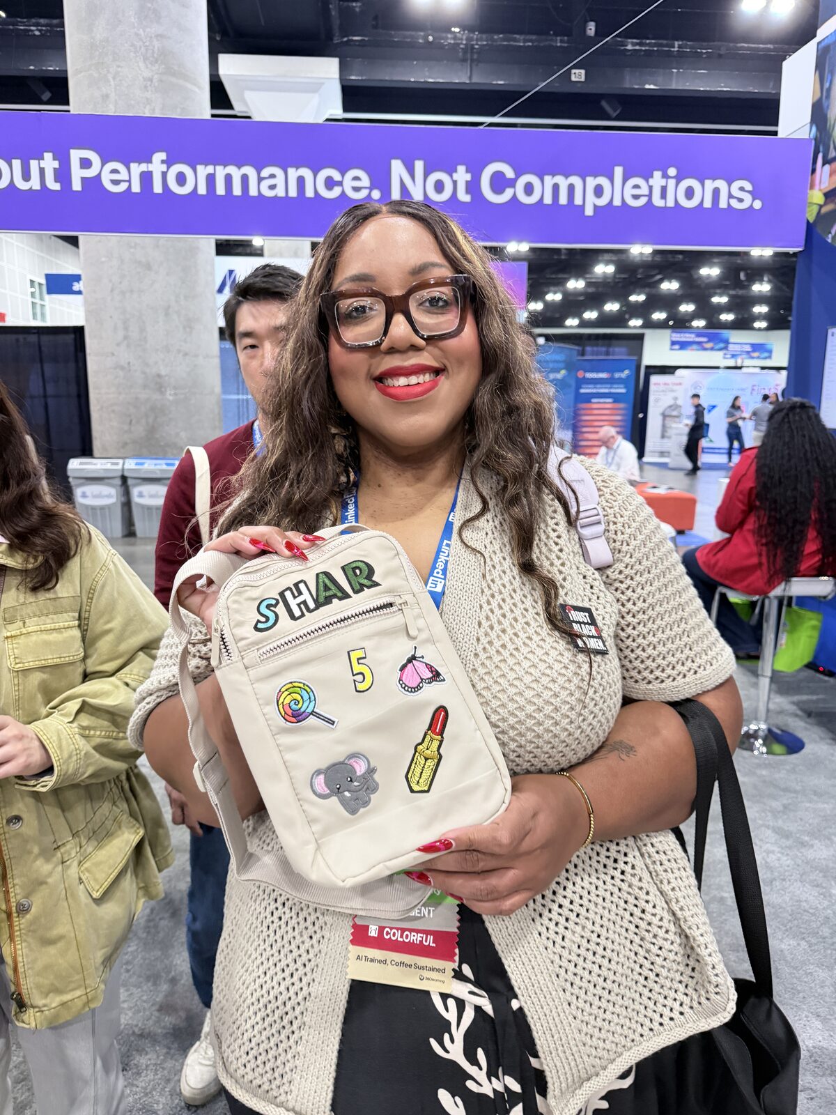 A smiling guest holding up a cream sling bag she personalized with letter patches and novelty patches